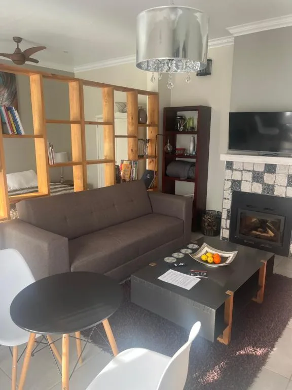 Modern living room with brown sofa, fireplace, TV, and wooden shelving unit