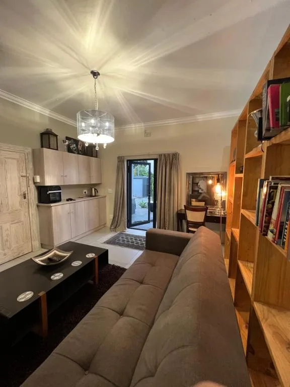 Open-plan lounge with sofa, kitchenette, and wooden shelving unit