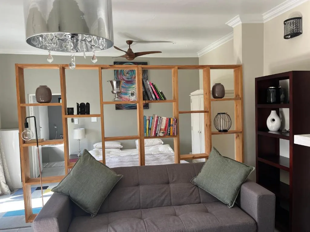 Modern lounge with dark sofa, decorative shelving, and pendant lighting fixture