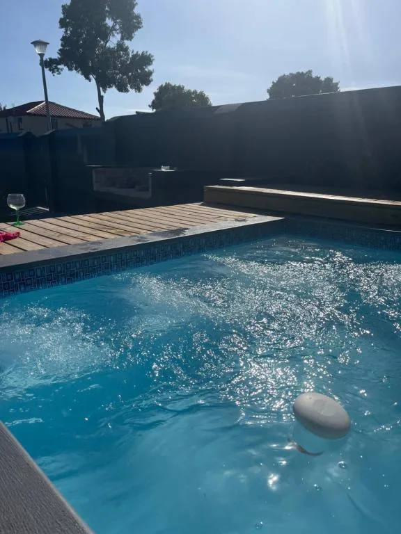 Sparkling blue swimming pool with wooden deck and dark privacy walls