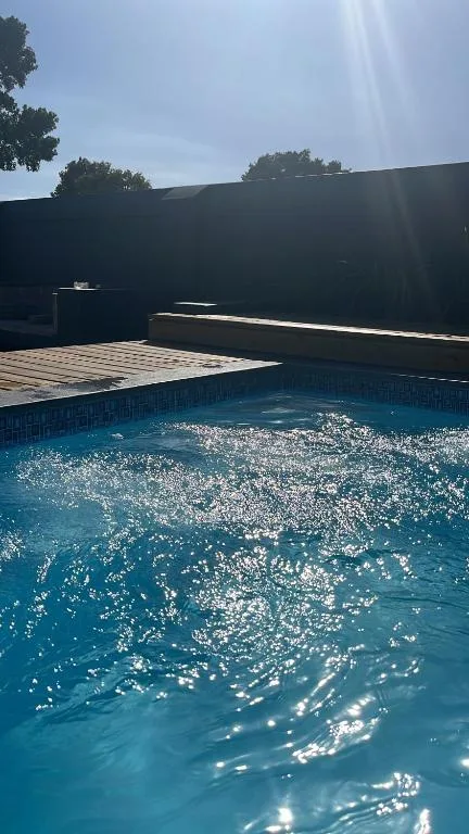 Sparkling blue swimming pool with wooden deck and dark wall backdrop