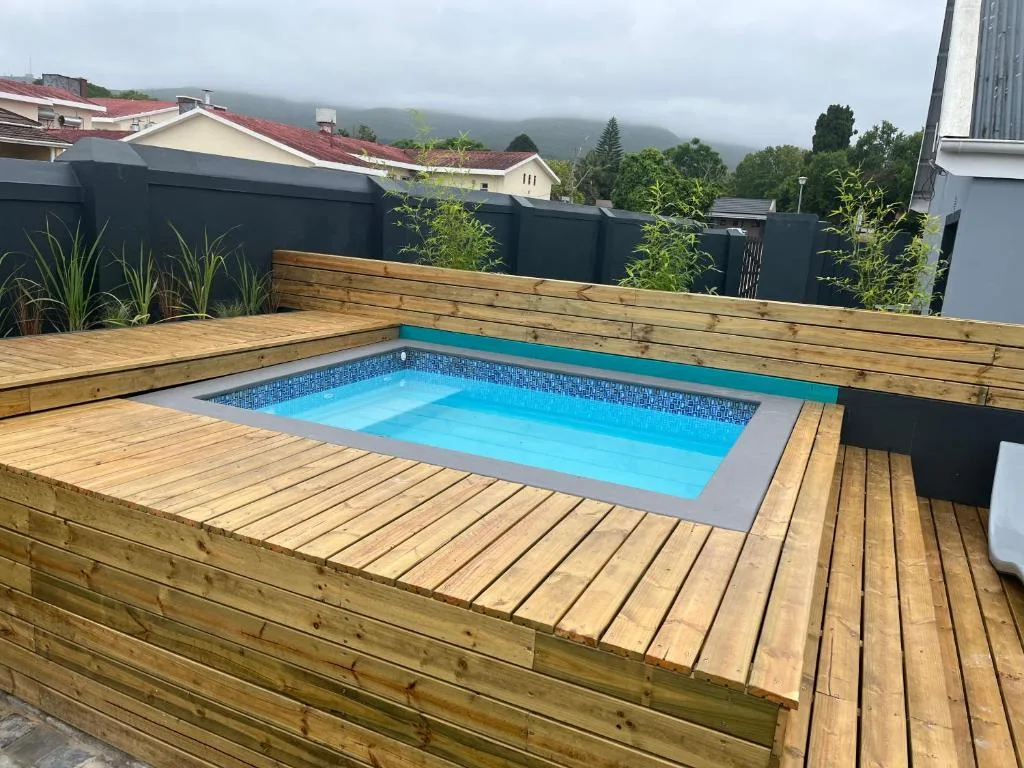 Bright blue swimming pool nestled in wooden deck with mountain backdrop