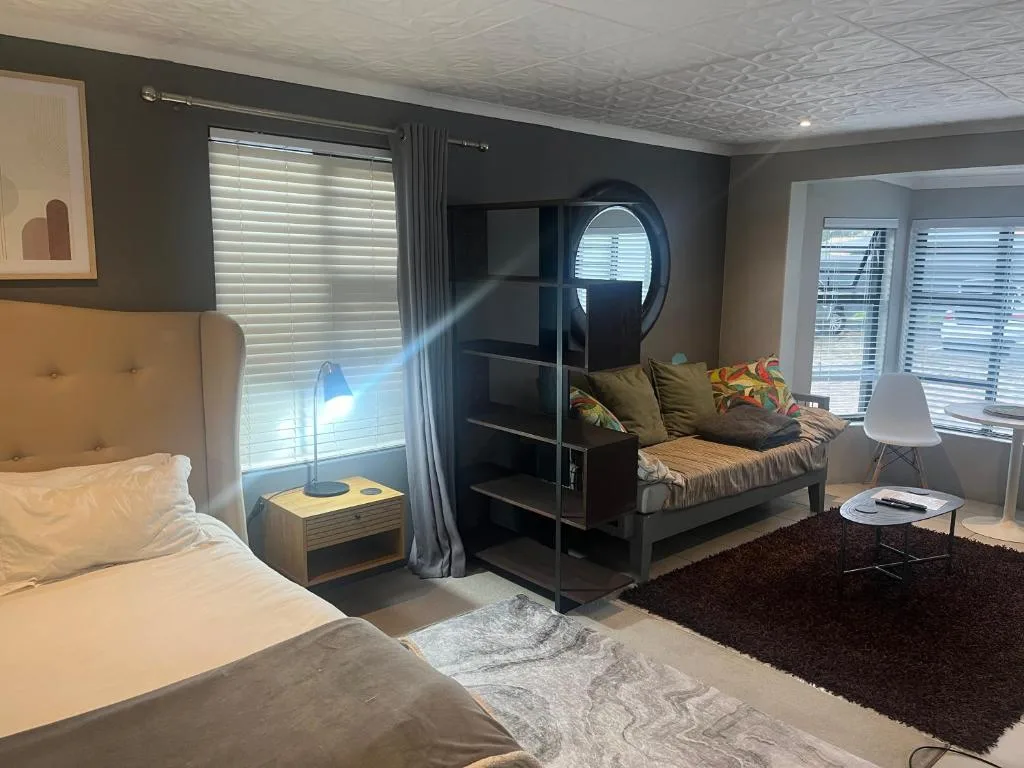 Modern bedroom with double bed, lounge seating area, and large windows