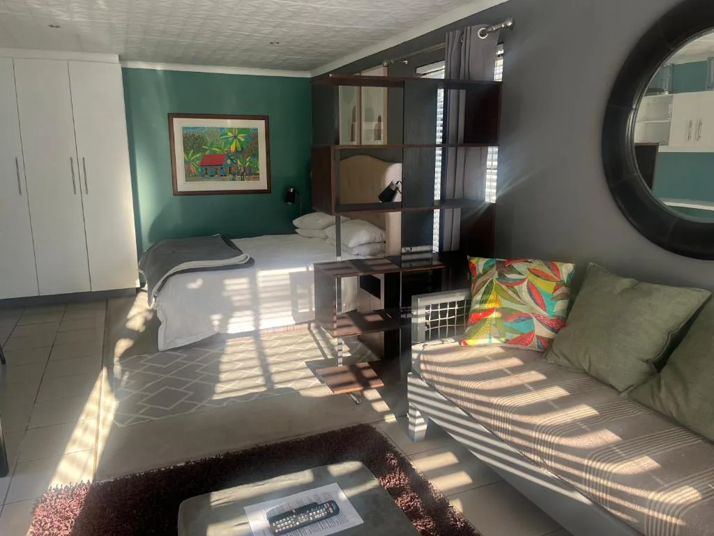 Bright studio bedroom with bed, lounge seating, and green accent wall