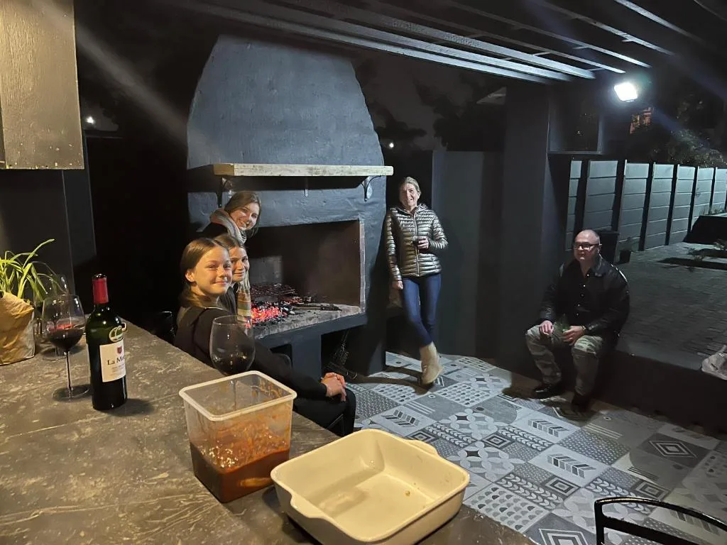 Outdoor patio area with fireplace, guests enjoying evening gathering with wine