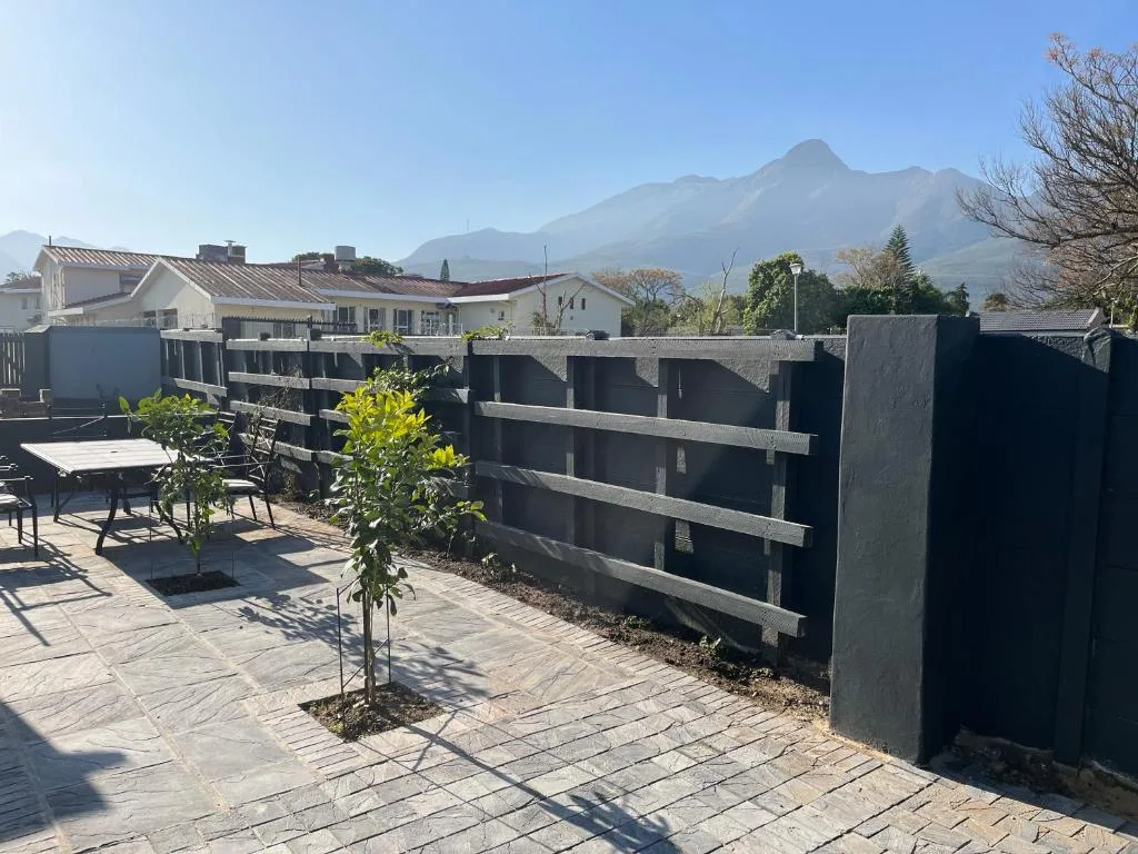 Paved patio with seating area and mountain views beyond fence