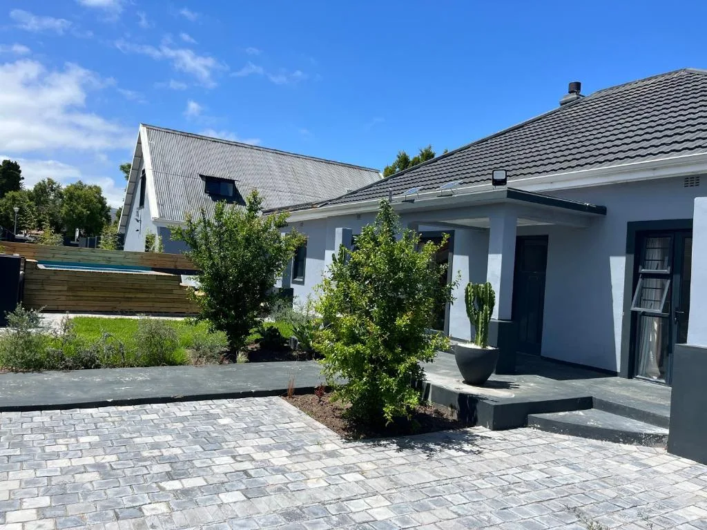 Modern white cottage with dark roof and paved courtyard entrance