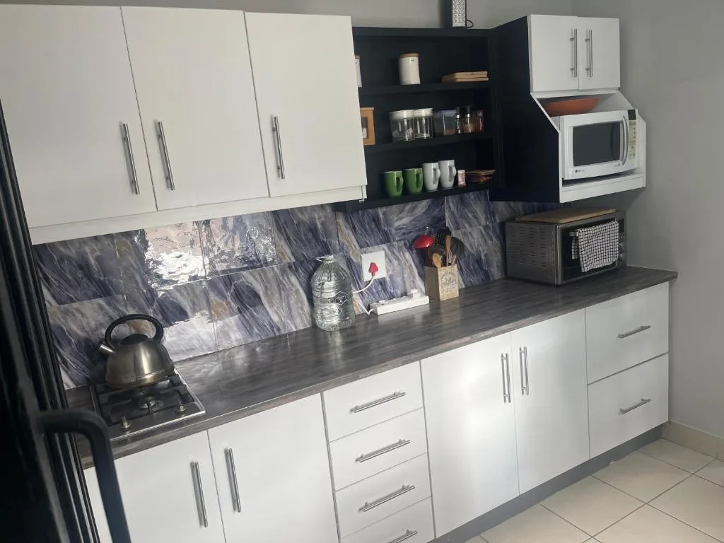 Modern kitchen with white cabinetry, dark countertop, and marble backsplash
