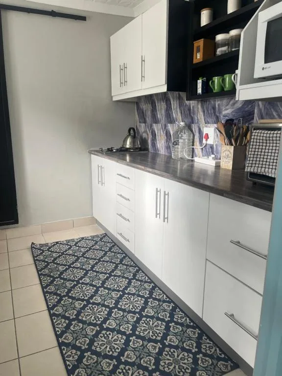 Modern kitchen with white cabinetry, dark countertop, and patterned runner rug