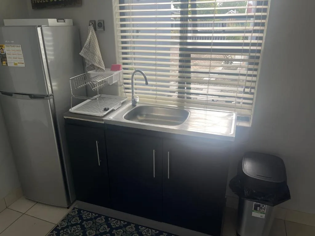 Compact kitchen with white fridge, black cabinetry, and stainless steel sink