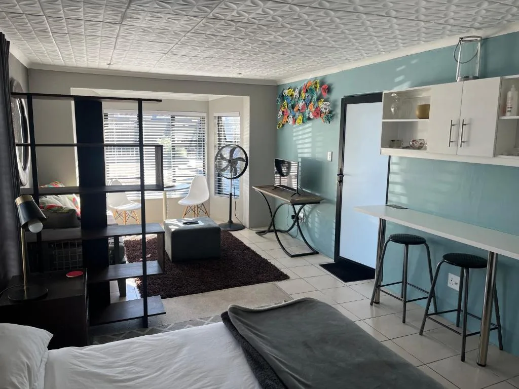 Open-plan studio with seating area, kitchenette, and modern turquoise accents