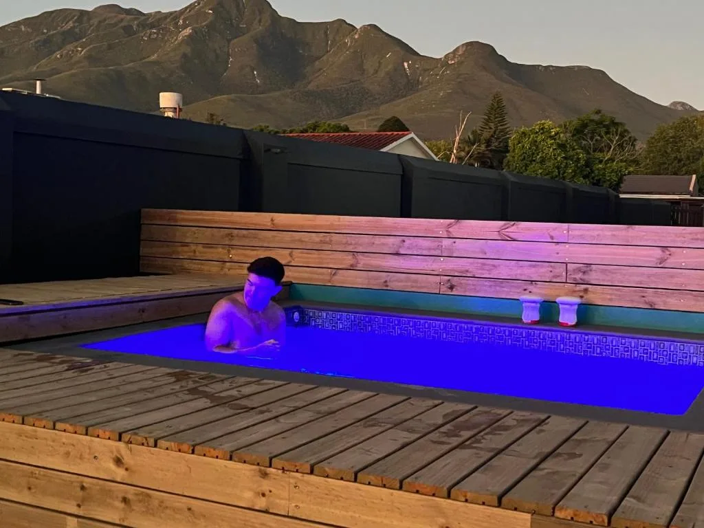 Illuminated infinity pool with mountain backdrop and wooden deck
