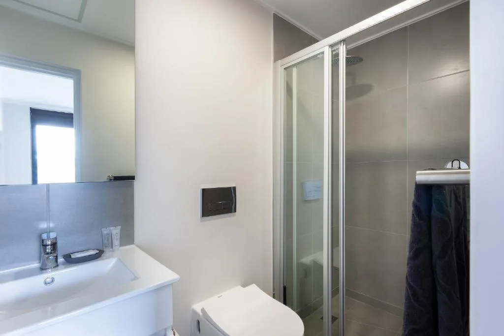 Modern bathroom with white vanity, toilet, and glass shower enclosure