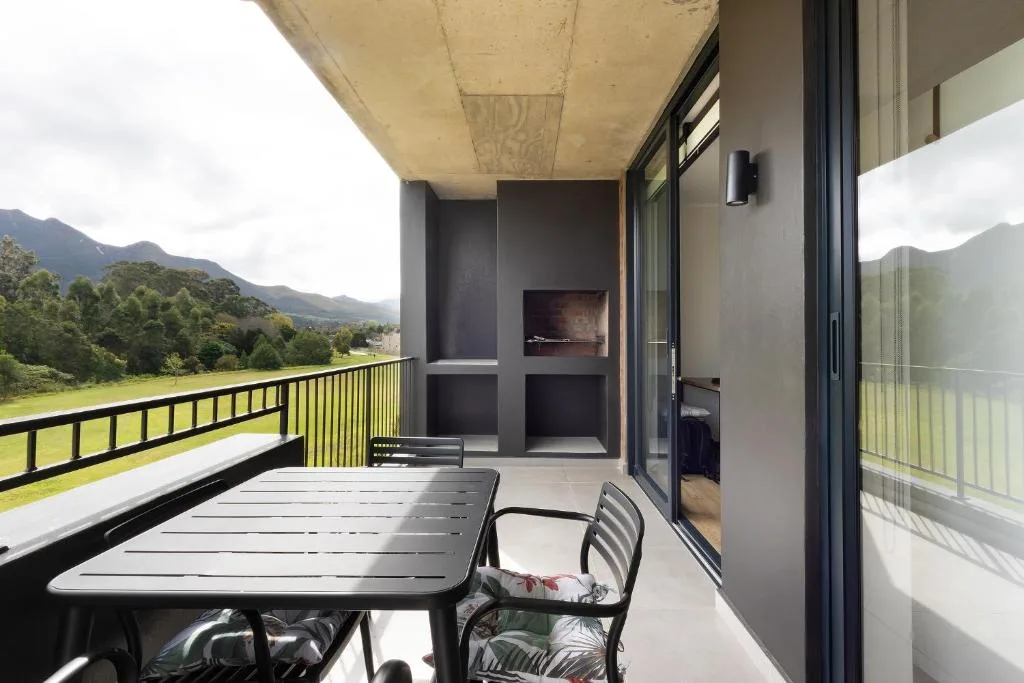 Modern balcony with dining table overlooking lush valley and mountains