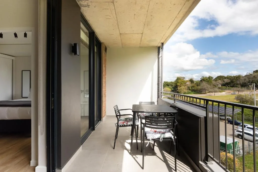 Covered balcony with dining table overlooking garden and distant landscape