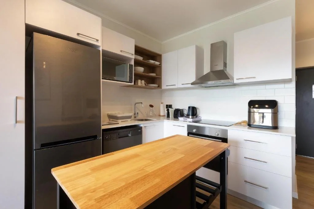 Modern kitchen with white cabinetry, stainless steel appliances, wooden counter