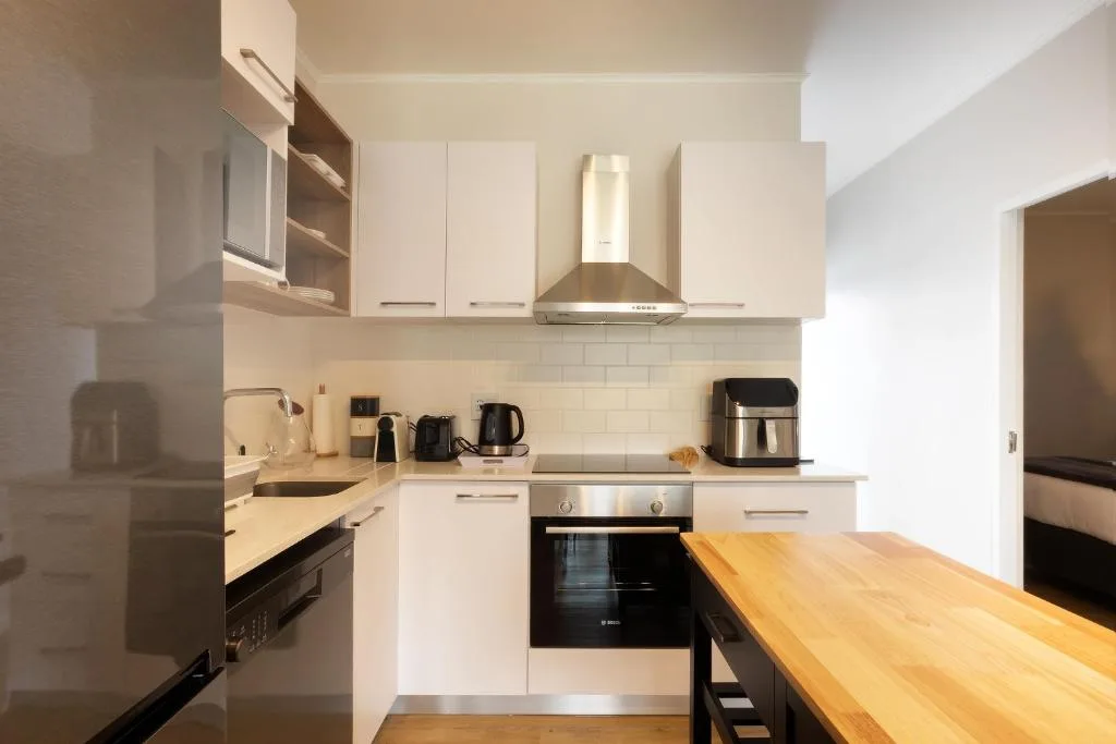 Modern white kitchen with stainless steel appliances and wooden counter
