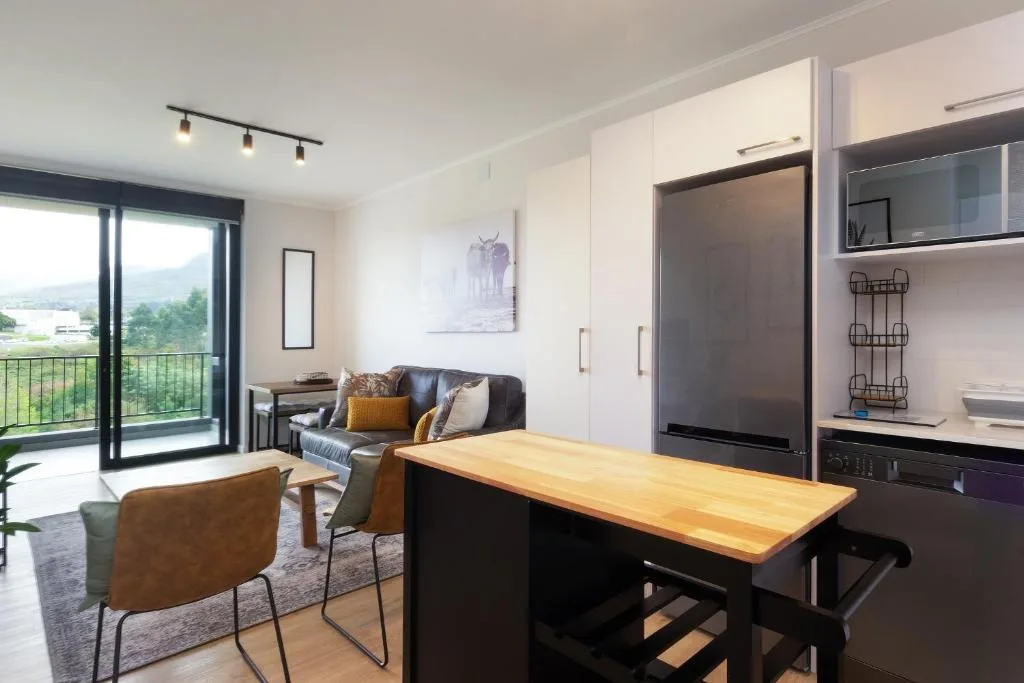 Open-plan living area with sofa, kitchen island, and mountain views through glass doors