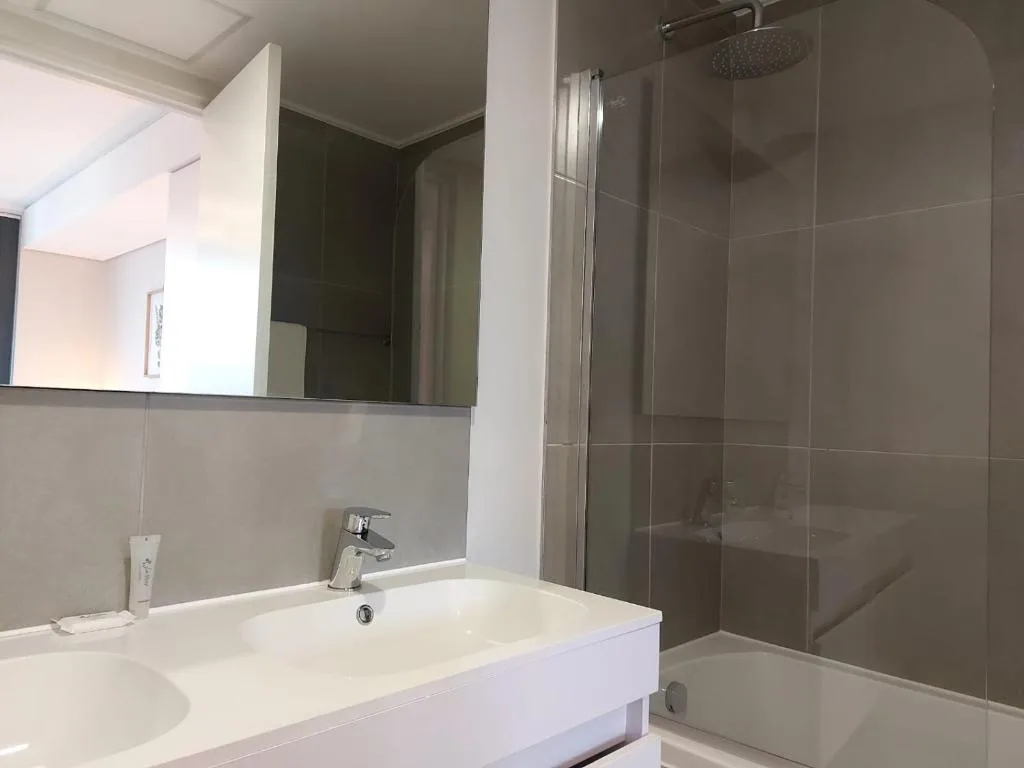 Modern bathroom with white vanity, mirror, and spacious walk-in shower enclosure