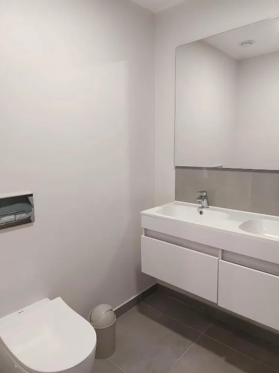 Modern bathroom with white vanity, sink, and toilet in clean space
