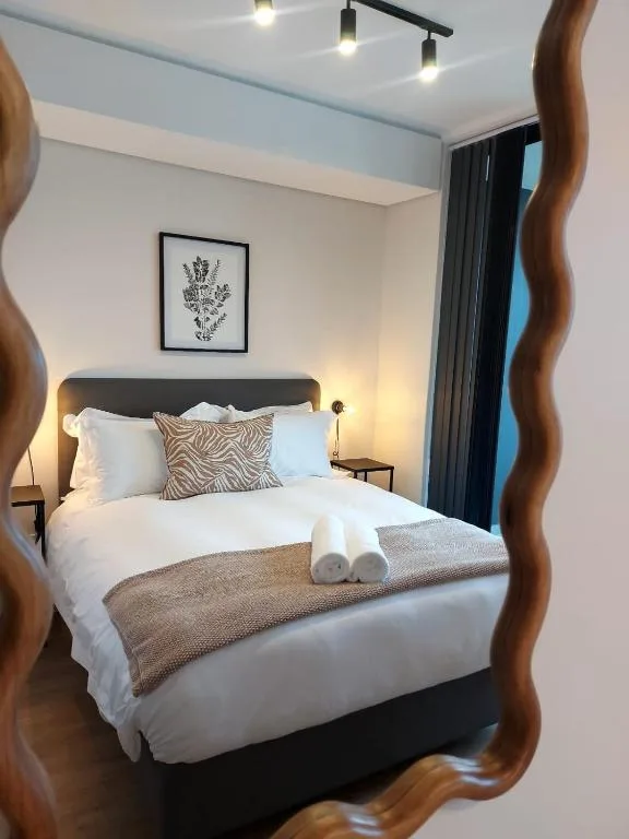 Modern bedroom with neatly made bed, warm lighting, and contemporary decor