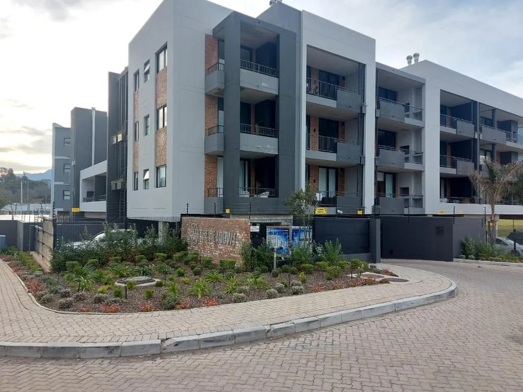 Modern multi-story apartment building with brick and gray facade, landscaped gardens