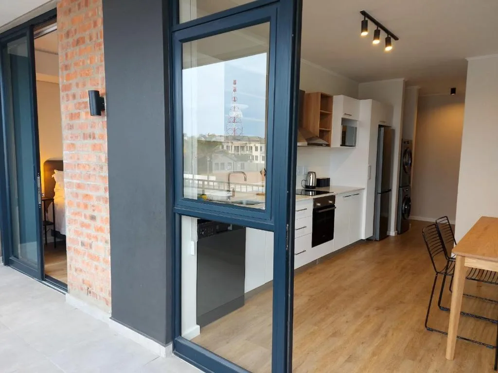 Modern kitchen with white cabinetry, stove, and scenic town view through glass doors