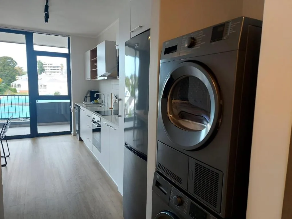 Modern kitchen with white cabinetry, stainless steel appliances, and laundry dryer