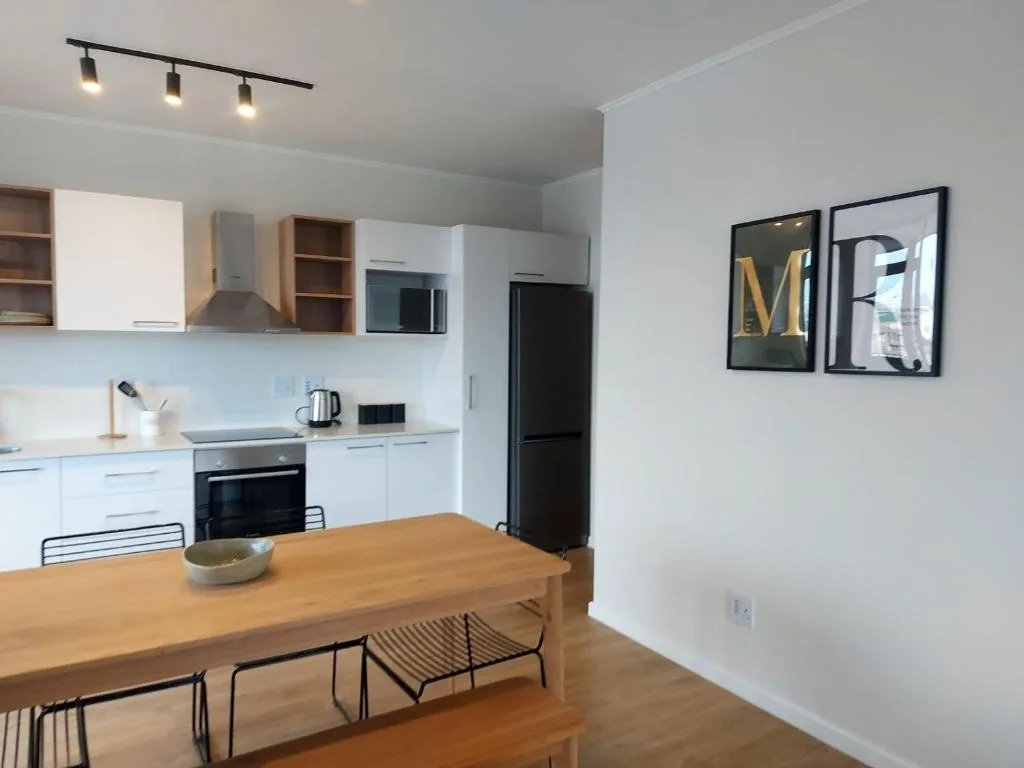 Modern white kitchen with wooden dining table and black appliances