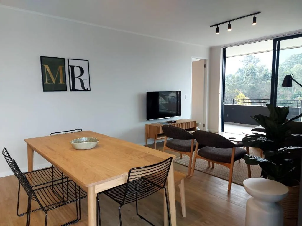 Open-plan lounge and dining area with wooden table, television, and garden views