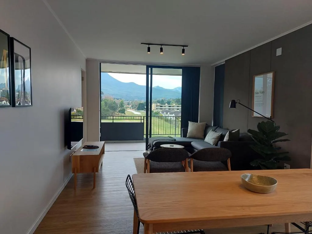 Modern lounge with mountain views, sofa, armchairs, and sliding glass doors