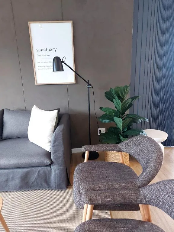 Modern lounge with gray sofa, upholstered chairs, and minimalist sanctuary artwork