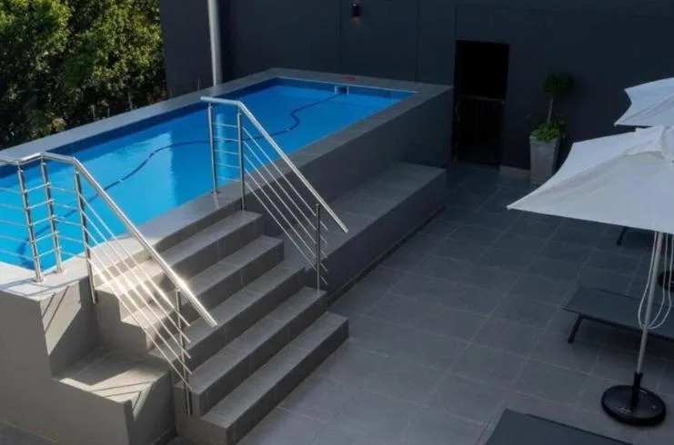 Modern rectangular swimming pool with metal railings and surrounding patio area