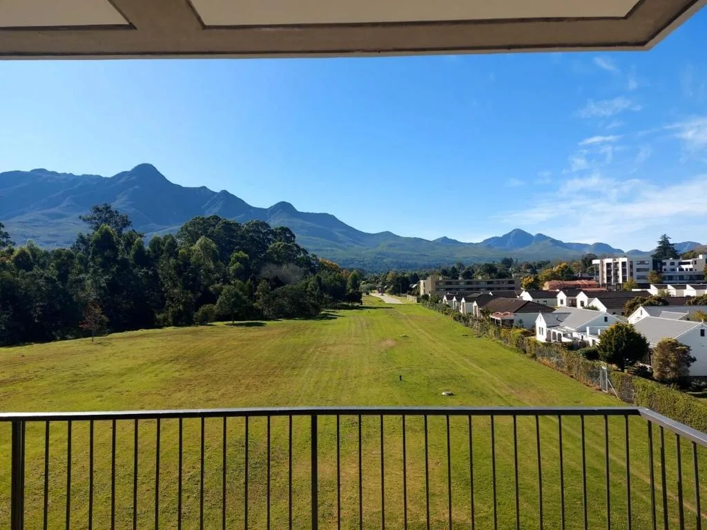 Panoramic mountain and valley vista from property deck overlooking lush grounds