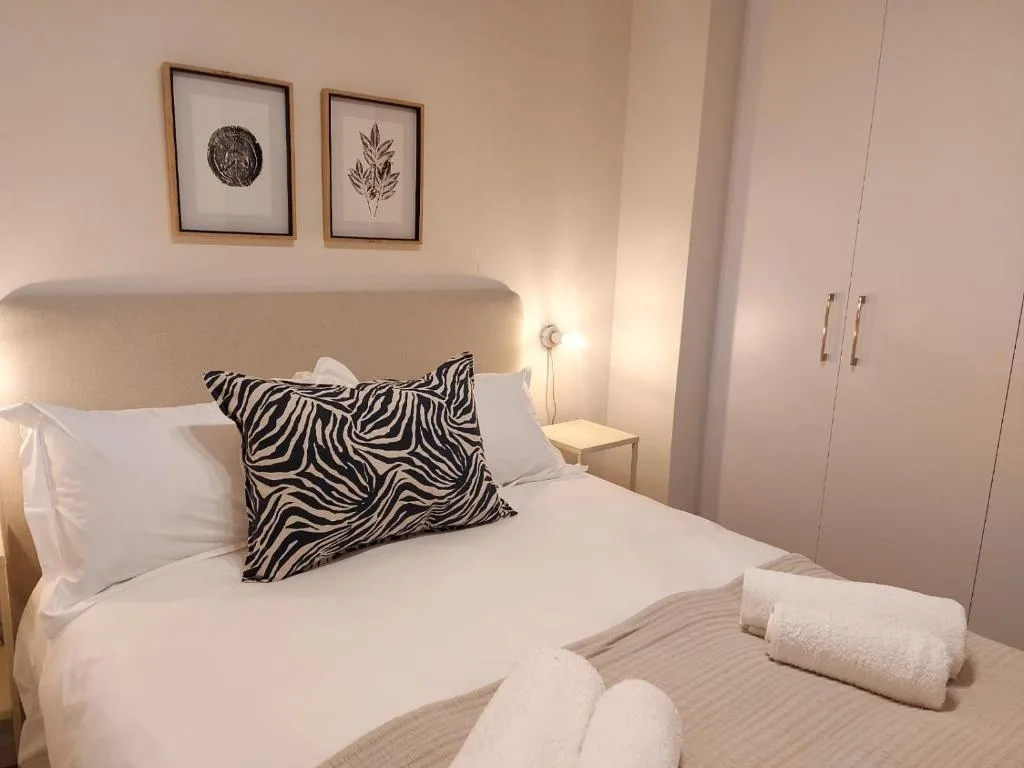 Modern bedroom with curved headboard, zebra-print pillow, and fresh white linens