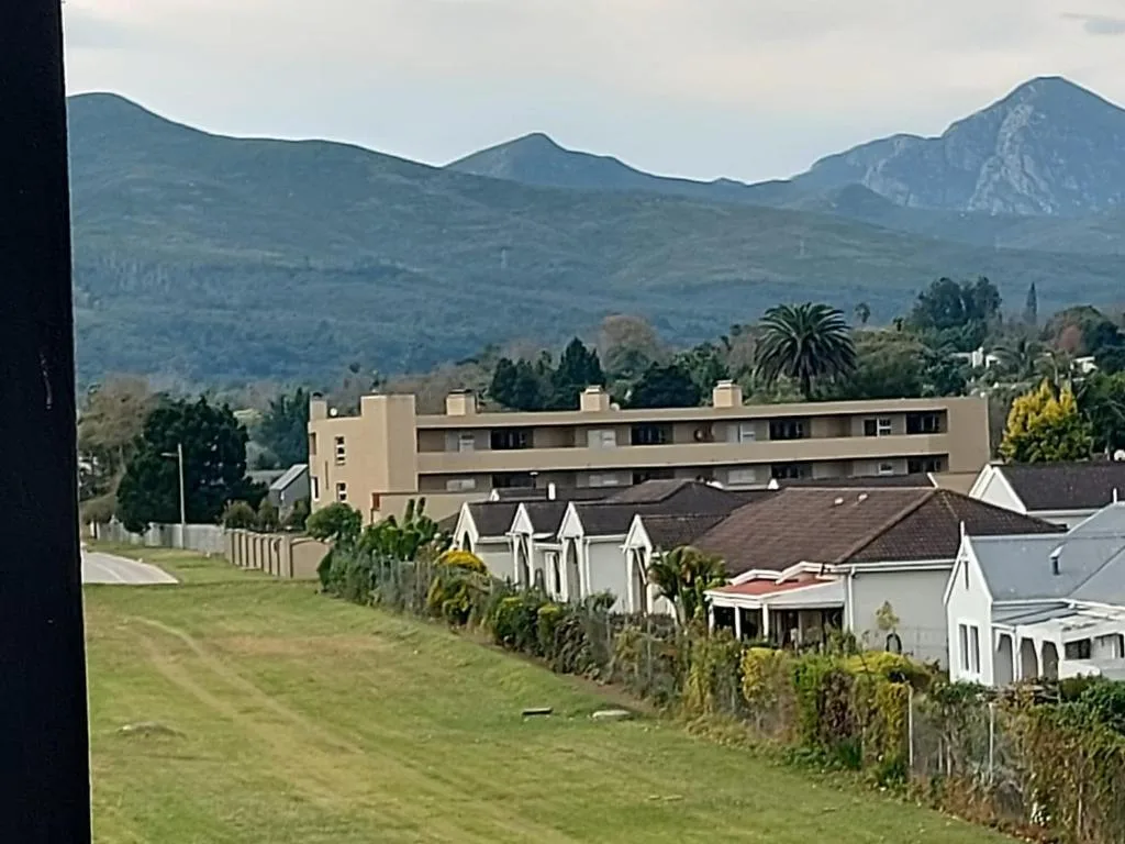 Mountain landscape backdrop with manicured lawns and residential properties below