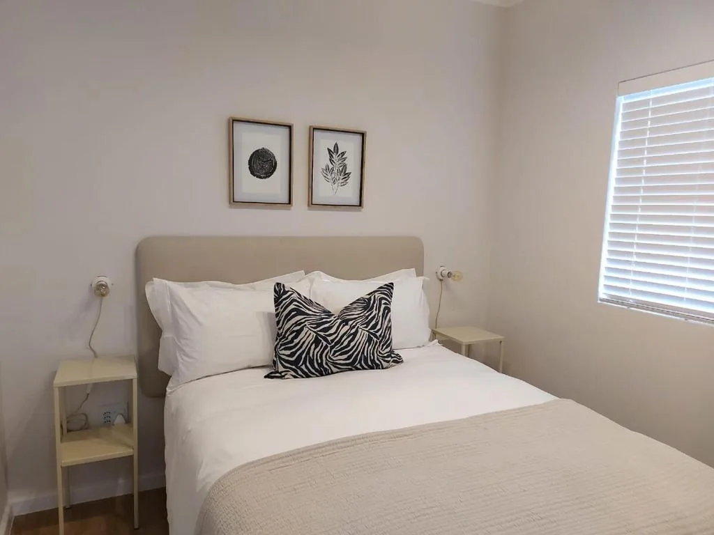 Bright bedroom with queen bed, neutral headboard, zebra print pillow, and framed wall art