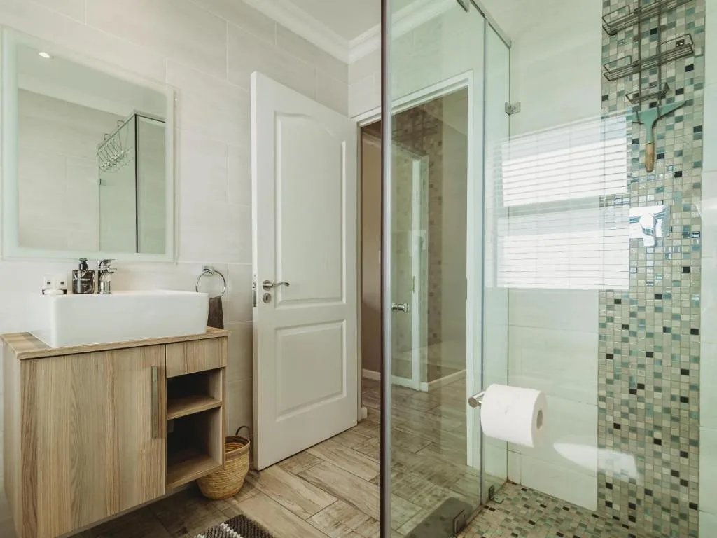 Modern bathroom with vessel sink, wooden vanity, and tiled shower enclosure