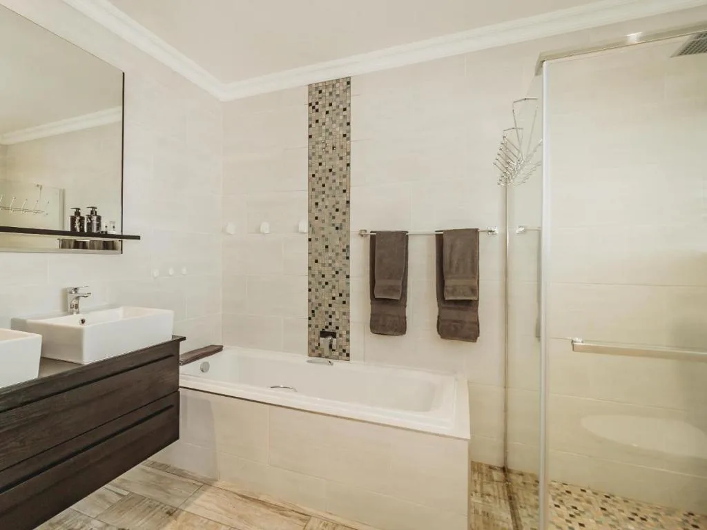 Modern bathroom with white bathtub, vanity sink, and glass shower enclosure