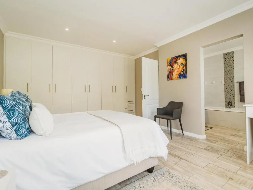 Spacious modern bedroom with white bed, built-in wardrobes, and ensuite bathroom