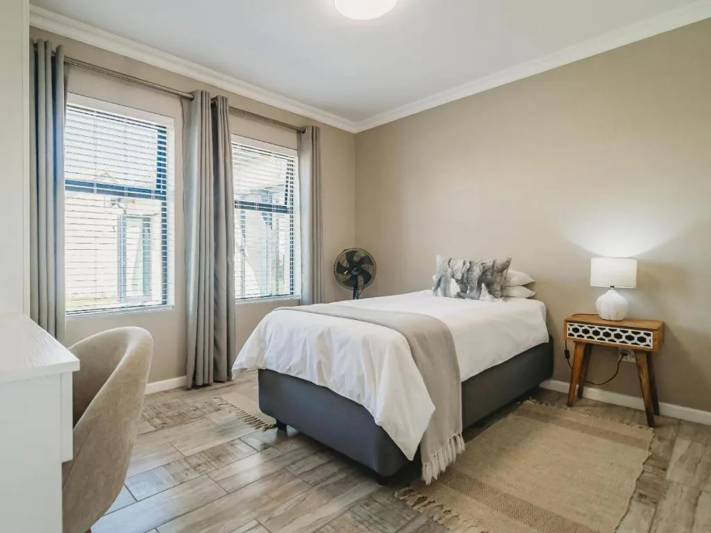 Bright bedroom with queen bed, neutral decor, and large windows