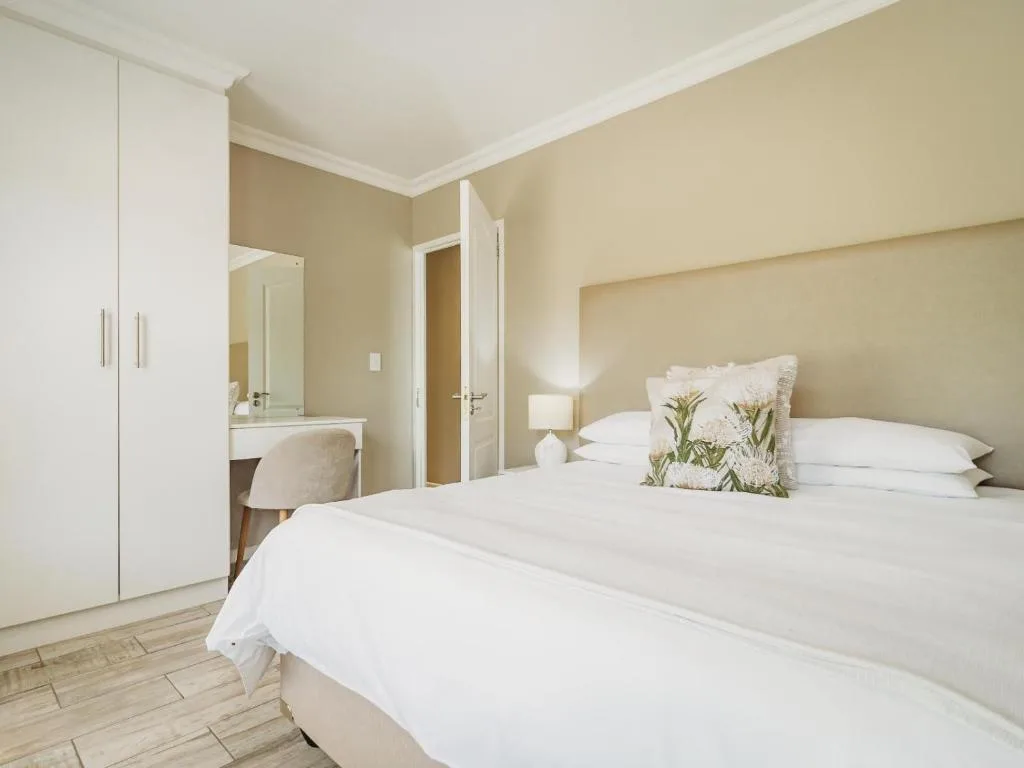 Bright bedroom with double bed, vanity desk, and en-suite bathroom entrance