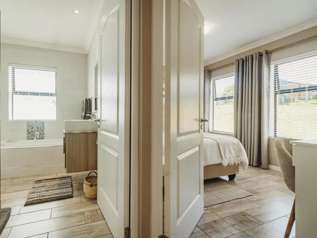 Bright modern bedroom with ensuite bathroom visible through open doors