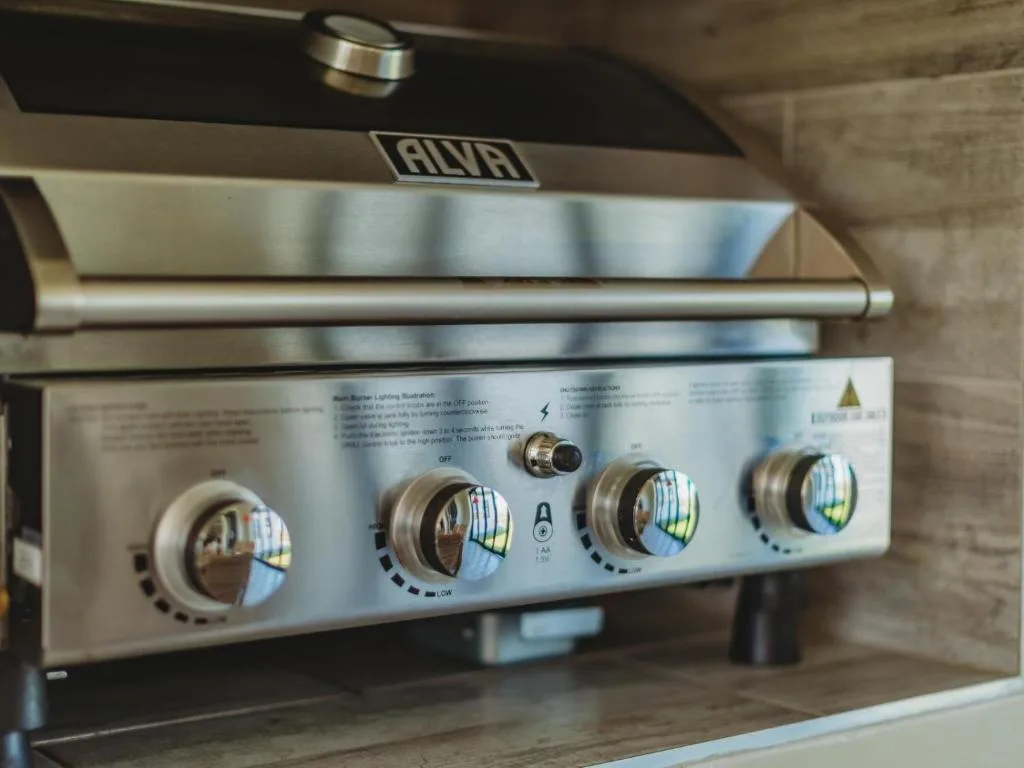 Stainless steel built-in braai grill with control knobs and hood vent