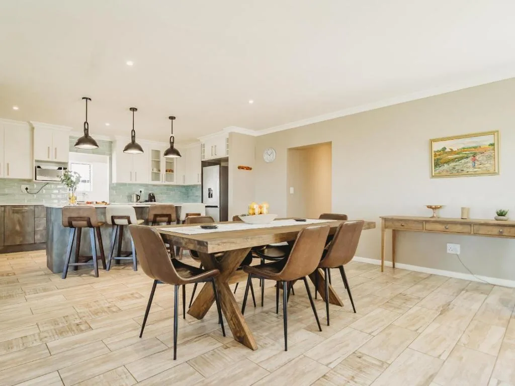 Open-plan dining area with wooden table and tan leather chairs adjoining kitchen