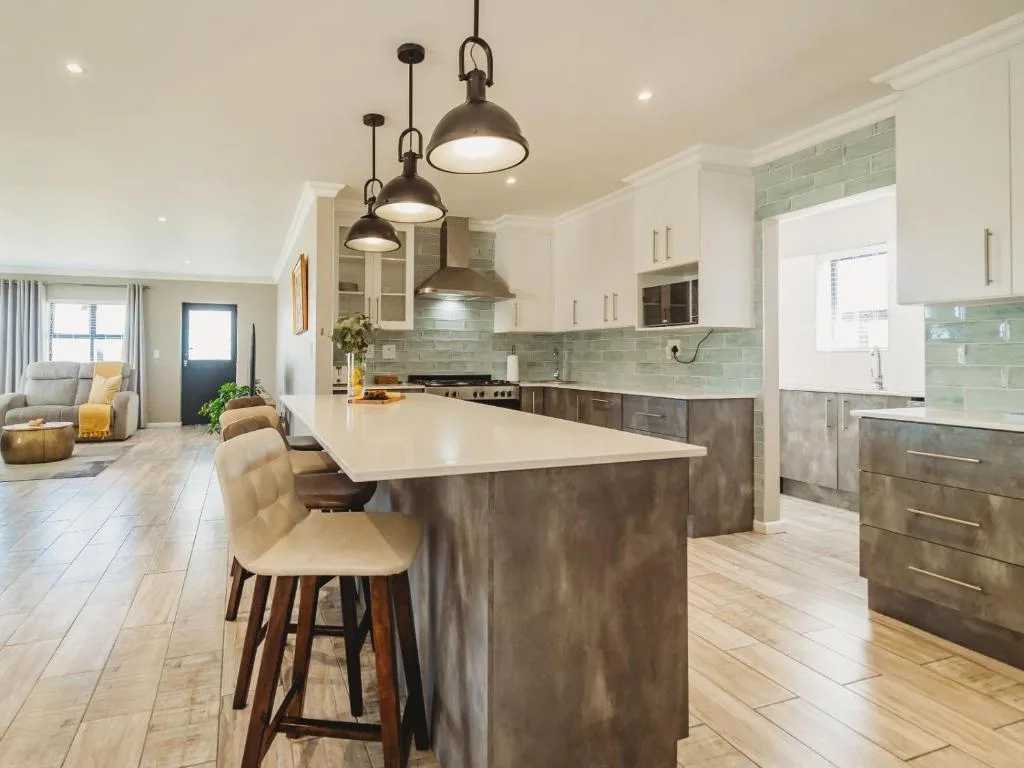 Modern kitchen with island, pendant lighting, and sage green backtile
