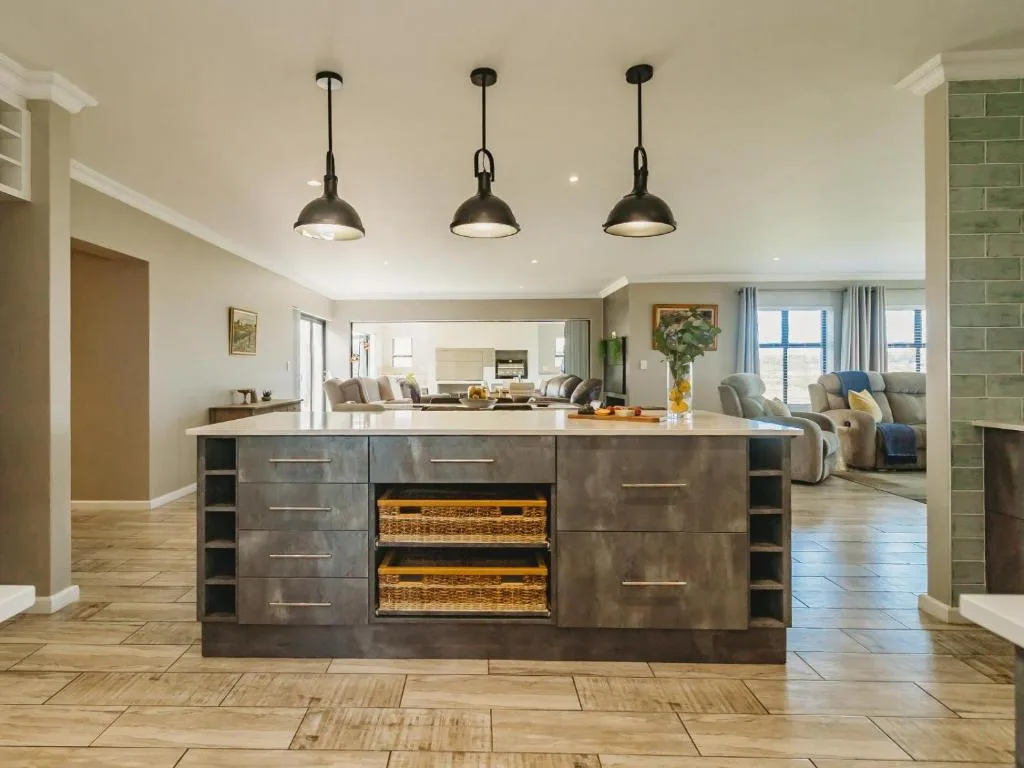 Modern kitchen island with dark cabinetry, pendant lighting, and woven storage baskets