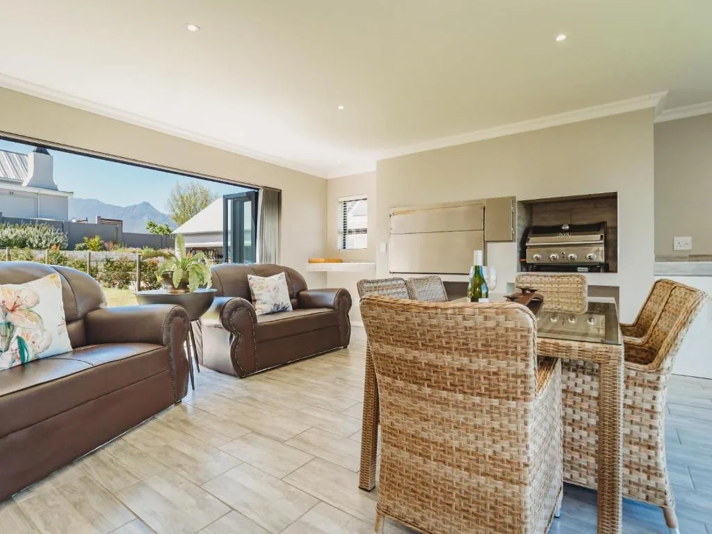 Spacious open-plan lounge with leather sofas and rattan chairs overlooking garden