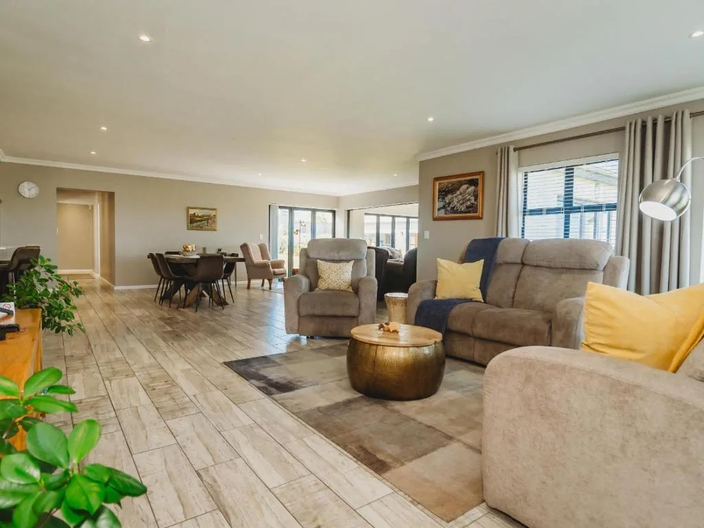 Spacious lounge with gray sofas, yellow accents, and ocean views through windows