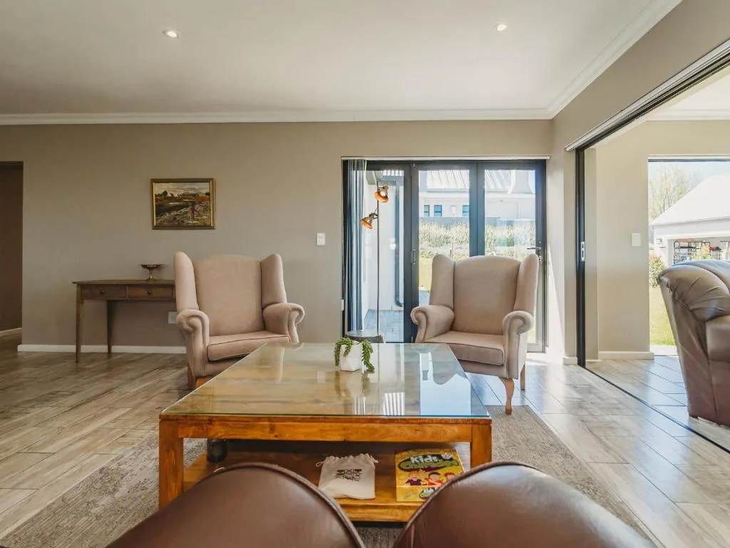 Spacious lounge with beige wingback chairs and wooden coffee table